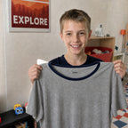 Garçon souriant tenant son t-shirt marqué au prénom avec le tampon pour vêtements enfant Tampiloo